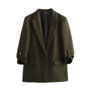 Detailed view of rolled three-quarter sleeves with gold button and flap pockets on olive blazer