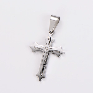 Macro detail of polished silver stainless steel cross pendant with a central zircon stone