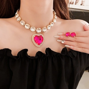 Close-up of gold heart necklace with red gems and matching round stud earrings on model