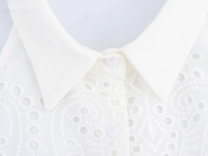 Dettaglio del ricamo in pizzo bianco e dei bottoni eleganti sulla scollatura