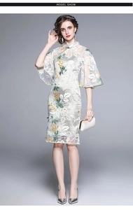Detailed close-up of floral embroidery on a white cheongsam dress with mandarin collar