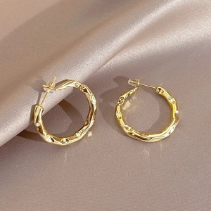 Macro detail of golden vintage enamel pearl earrings with irregular hammered metal texture