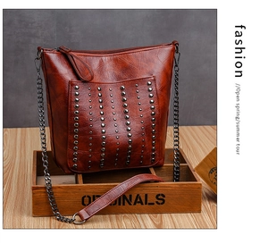 Close-up of vintage brown PU leather bag with metallic rivet studs and chain strap