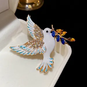 Elegant peace dove brooch with white enamel, sparkling rhinestones and gold-plated finish