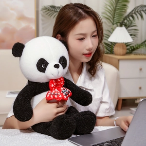 Detail of soft teddy plush panda doll with a red Love heart bow tie in warm home setting