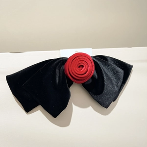 Détail d'une grande barrette nœud en velours noir avec une rose en velours rouge au centre