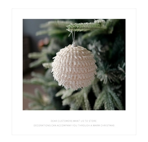 Close-up of white knitted foam ball ornament hanging on a Christmas tree with soft lighting
