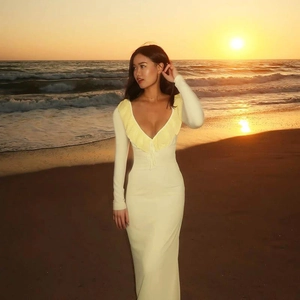Detail of ruffle trim and deep V-neckline on a slim-fit yellow long-sleeved dress
