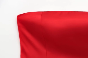 Vue détaillée du tissu en satin rouge vif montrant la texture lisse et les coutures fines