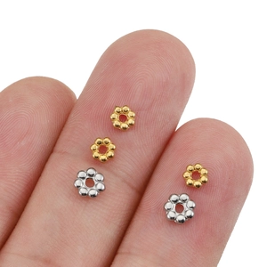 Small gold and silver flower spacer beads for DIY jewelry making on fingertips