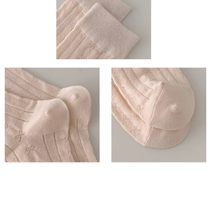 Detail view of pink knitted socks featuring delicate bow jacquard and reinforced toe seams