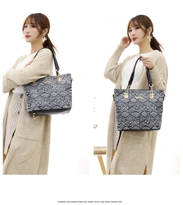 Detail view of snakeskin pattern tote bag with golden hardware and glossy black handles