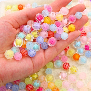 Colorful pumpkin-textured acrylic beads for DIY jewelry making held in a person's hand