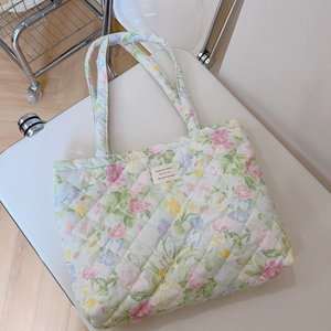 Detailed close-up of floral quilted tote bag featuring a beige woven logo and diamond texture