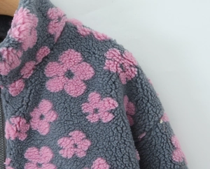 Detail of dark grey fleece sweatshirt featuring pink floral patterns and high neck collar