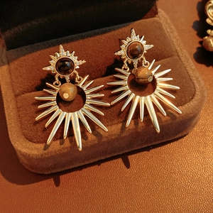 Macro detail of starburst drop earrings featuring brown tigers eye stone and gold plating