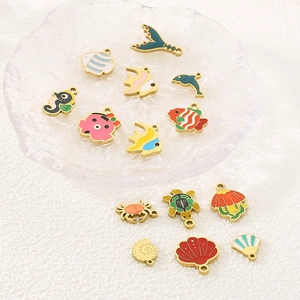Detailed macro shot of gold ocean-themed pendants with colorful enamel on a textured plate