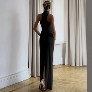 Back view of a slim black high-neck sleeveless dress with a side slit and white heels