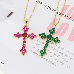 Detail of cross pendants with emerald green and rose pink crystals on gold chains