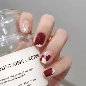 Close-up of wine red and nude press-on nails with glitter and wave patterns