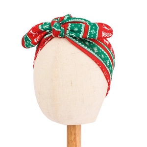 Detail of baby Christmas turban hat with red and green bow and snowflake patterns