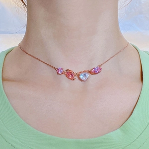 Detail of rose gold necklace with pink and light purple gems on a female model neck