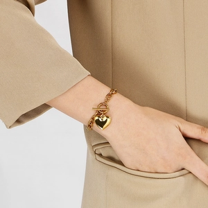 Detail shot of a chunky gold heart pendant bracelet with a stylish OT toggle clasp