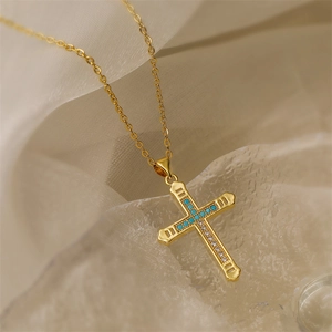 Macro shot of gold cross necklace with turquoise and cubic zirconia on ice cubes