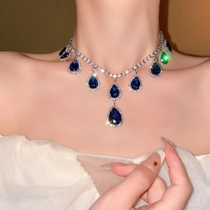 Elegant blue teardrop earrings with halo diamonds worn by a model for a luxury fashion look