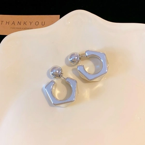 Detailed view of silver geometric hexagon C-shaped earrings on a white ceramic tray