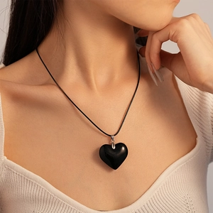 Vintage style black heart pendant necklace with cord for women on white knitwear
