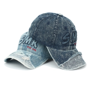 Détail de casquettes en jean délavé avec bords effilochés et broderie SMK 3D