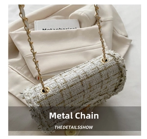 Detailed close-up of white tweed bag texture with gold thread and metal chain links