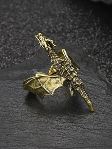 Macro shot of vintage bronze dragon ring on dark rock base showing detailed enamel scales