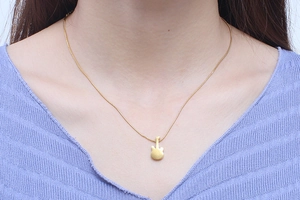 Close-up of a minimalist golden guitar pendant necklace on model's neck detail