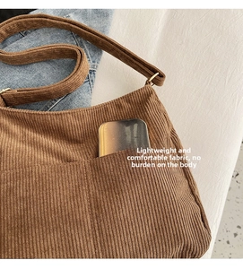 Detail view of brown corduroy shoulder bag showing texture and functional front pocket