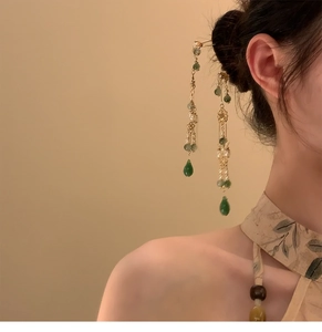 Épingle à cheveux chinoise avec fleur en verre verte et longs pompons dorés sur un mannequin
