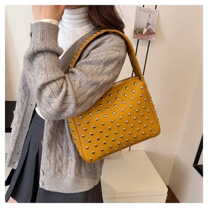 Detail of yellow rivet shoulder bag with silver studs and lychee pattern leather texture