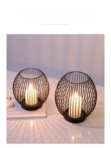 Detail of Nordic black metal birdcage candle holders with white pillars in warm light