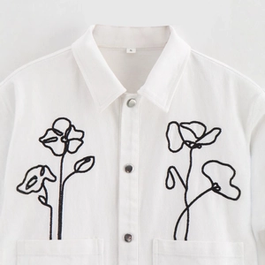 White long-sleeve jacket with black floral embroidery and buttoned collar detail