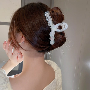 Détail d'une pince à cheveux florale irisée portée sur un chignon élégant