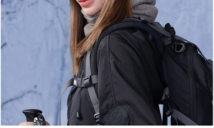 Detail of outdoor winter jacket sleeve with logo, hiking backpack and trekking poles