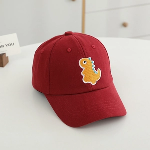 Détail d'une casquette enfant rouge avec broderie de dinosaure jaune et nageoires bleues