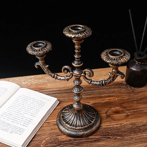 Vintage bronze three-arm candelabra with ornate European scrollwork on a wooden table