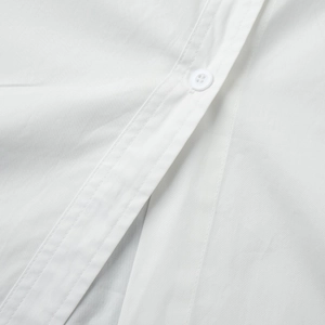 Detailed macro view of white cotton dress placket with fine stitching and resin button