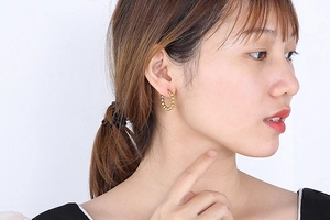 Close-up of a woman wearing gold beaded hoop earrings in a minimalist French chic style