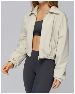 Detail of a lightweight beige zip-up jacket showing windproof fabric and elastic cuffs