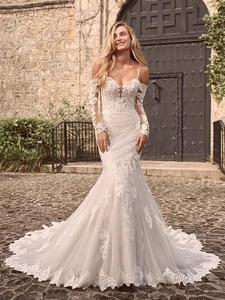Detailed view of white mermaid wedding dress with off-shoulder lace sleeves and embroidery