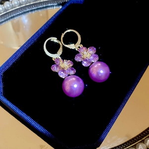 Detail shot of purple flower pearl earrings on velvet tray with crystal accents