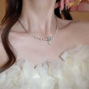 Macro detail of a French style pearl necklace with square pendant on an elegant lace dress